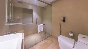 A modern bathroom with a glass-enclosed shower, a white toilet, and a sink.