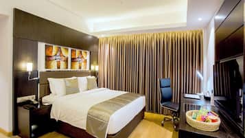 Habitación de hotel con una cama grande, un escritorio con silla, un televisor y una obra de arte en la pared.