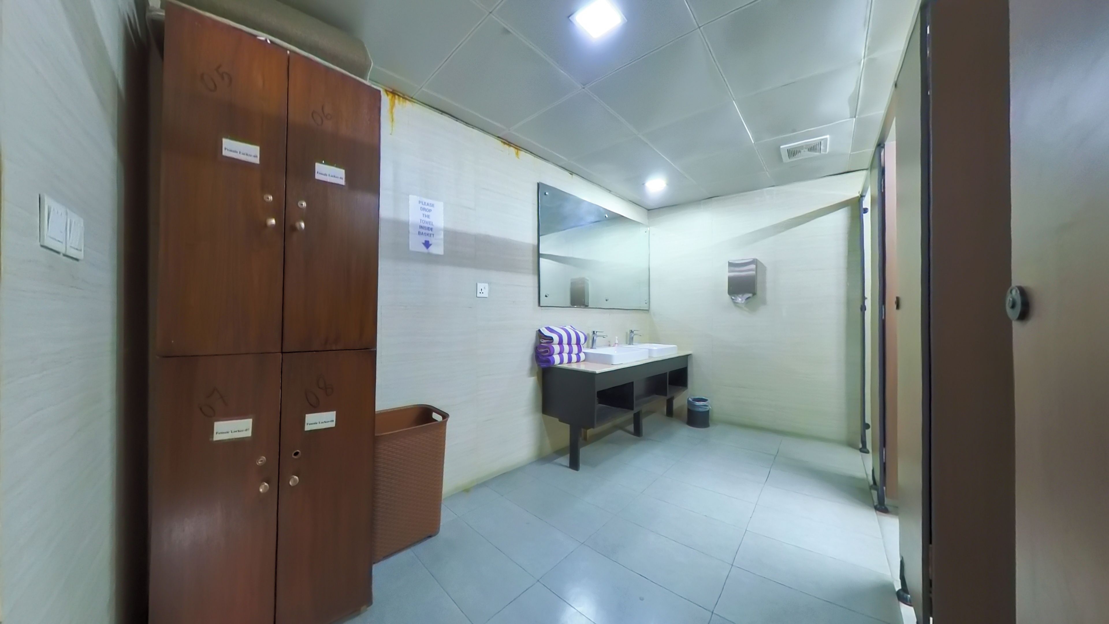 Un baño con lavamanos, espejo y taquillas de madera.