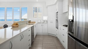 Una cocina moderna con armarios blancos, electrodomésticos de acero inoxidable y una isla grande con un cuenco de fruta.