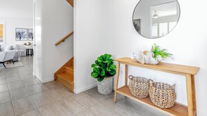 Un interior moderno con una escalera, una consola con cestas y un espejo redondo en la pared.