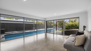 Zona d'estar àmplia amb un gran finestral corredís que dona a un pati amb piscina.