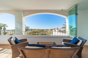 Ein Balkon mit Korbmöbeln und freiem Blick auf den Strand und die Gebäude.