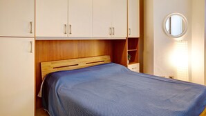 Un dormitorio con cabecera de madera, colcha azul y armarios blancos.
