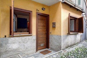 A building with a wooden door, a window with a wooden frame, and a stone-paved entrance. - Holiday Apartment 'Foresteria al Cantun' with Wi-Fi (Sondrio)