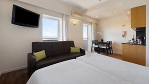 Een hotelkamer met een bed, een slaapbank, een televisie, een eettafel en een kitchenette.