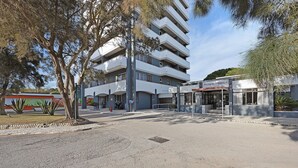Een meerhoog gebouw met een plat dak, een bordje met de tekst 'Pestana Alvor Atlantico', en een verhard gebied ervoor.