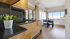 Una cocina moderna con armarios de madera, encimera de granito y una zona de comedor con mesa y sillas.