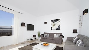 A modern living room with a grey sofa, a white coffee table, and a flat-screen TV mounted on the wall. - Vacation Villa 'Benedicte' with Sea View, Wi-Fi and Air Conditioning (Puerto del Carmen)