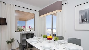A modern dining room with a white table set for four, a large window with a view, and a pendant light above the table. - Vacation Villa 'Benedicte' with Sea View, Wi-Fi and Air Conditioning (Puerto del Carmen)