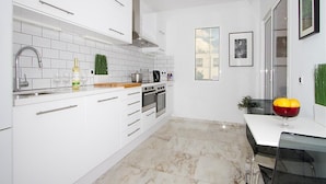 A modern kitchen with white cabinets, a stainless steel range, and a marble floor. - Vacation Villa 'Benedicte' with Sea View, Wi-Fi and Air Conditioning (Puerto del Carmen)