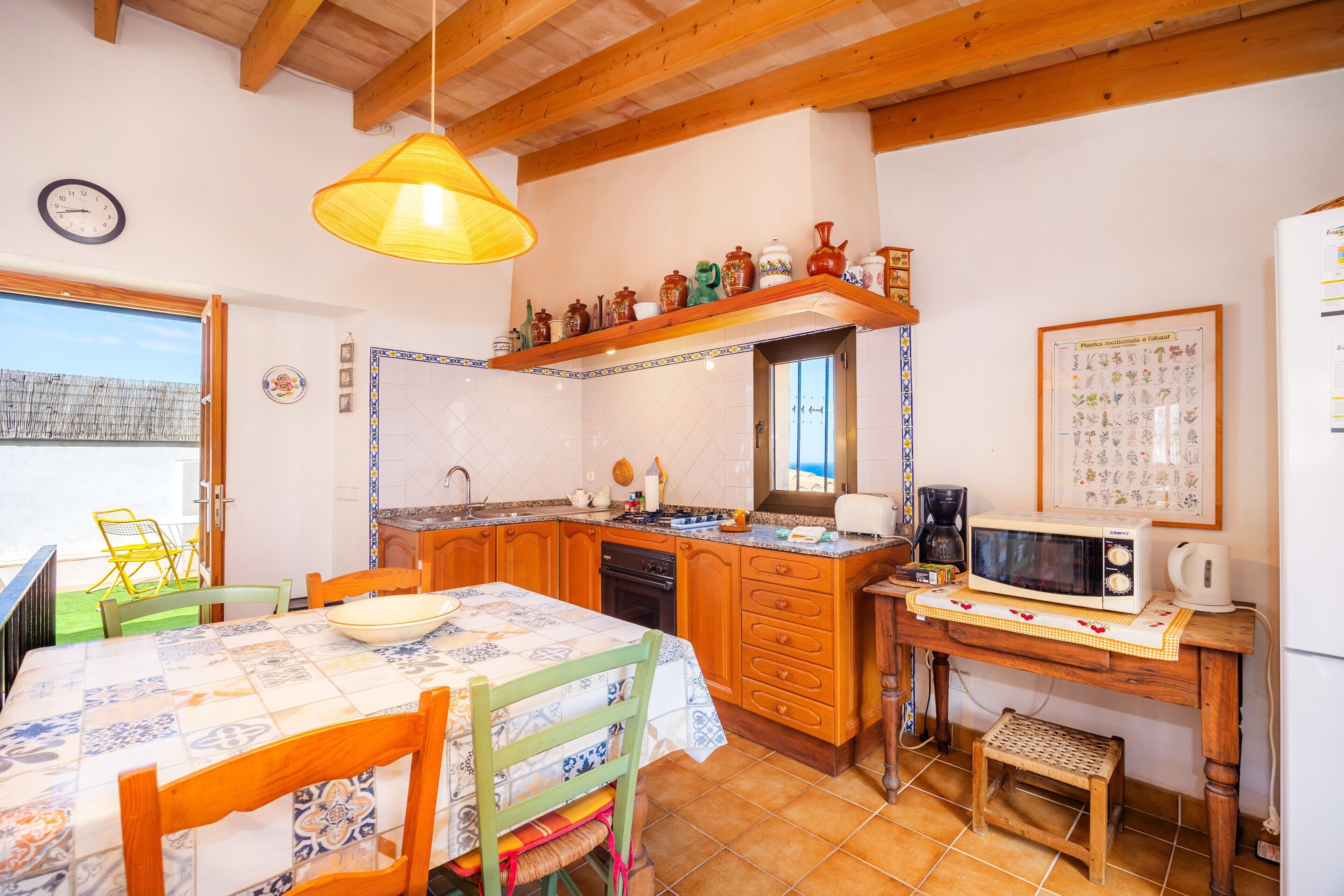 Una cocina con armarios de madera, microondas, fregadero y una mesa de comedor con sillas.