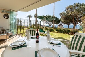 A dining table set for two with a bottle of wine, white plates, and green napkins.