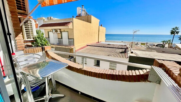 Una terraza en la azotea con un panel solar, una mesa de metal y vistas al mar.