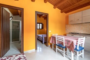 A compact kitchen with a table and chairs, a visible shower area, and a small bedroom with a bed. - Holiday Home 'Villa Salvo' with Sea View, Garden & A/C (pachino)