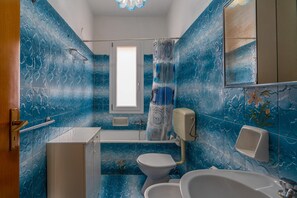 A bathroom with a bathtub, toilet, and sink, featuring blue marble tiles and a window. - Holiday Home 'Villa Salvo' with Sea View, Garden & A/C (pachino)