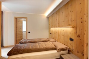 Ein Schlafzimmer mit einer Holzpaneelausstattung, einem Bett mit beigefarbener Bettwäsche und einer kleinen Holzbank.