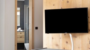 Une salle de bain moderne avec des toilettes, une douche en verre et un mur en bois sur lequel est fixé un téléviseur.