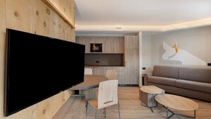 Un salon moderne doté d’un téléviseur à écran plat, de planchers en bois, d’un canapé et d’un coin repas avec des chaises.