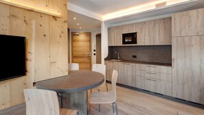 Une cuisine moderne avec des meubles en bois, un four à micro-ondes encastré et un coin repas comprenant une table ronde et des chaises.