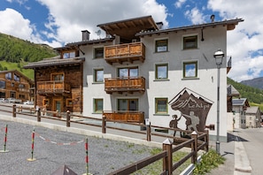 A hotel with multiple balconies, a mountain view, and a sign indicating it's a hotel.
