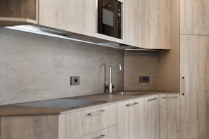 A modern kitchen with a stainless steel sink, wooden cabinets, and a built-in microwave.