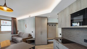 A modern kitchen with a built-in oven, a dining area with a wooden table, and a sofa.