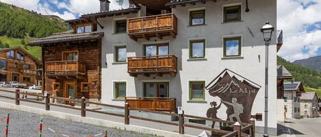A hotel with multiple balconies, a mountain view, and a sign indicating it's a hotel.