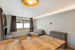 A modern room with a wooden dining table, a sofa, and a cabinet.