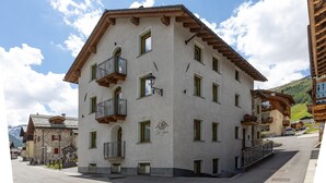 Ein mehrstöckiges Gebäude mit Balkonen, Blick auf die Berge und einem Schild, das ein Hotel anzeigt.