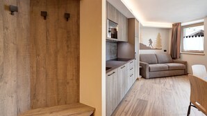 Eine moderne Küche mit Holdekor, einem eingebauten Ofen und einem grauen Sofa in einem Wohnbereich mit Fenster.