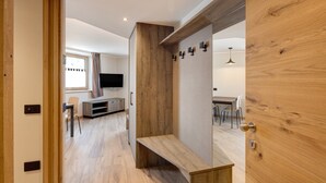 Un intérieur moderne avec un banc en bois, un coin repas et un téléviseur en arrière-plan.