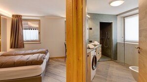 Une chambre avec un lit, un lave-linge et un espace douche.