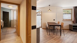 Un intérieur moderne avec un plancher en bois, un coin repas comprenant des chaises, une table et une fenêtre avec des rideaux.