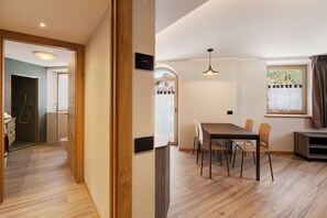 Un interior moderno con suelo de madera, un área de comedor con sillas, una mesa y una ventana con cortinas.