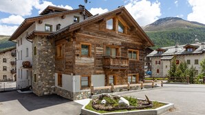 Un bâtiment en bois doté de balcons, de murs en pierre et avec une montagne en arrière-plan.