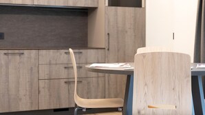 Une cuisine moderne avec des meubles en bois, un four encastré et une table de salle à manger ronde, accompagnée d’une chaise.