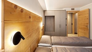 Une chambre à coucher avec une tête de lit en bois, un lit avec une literie beige et une armoire aux portes grises.