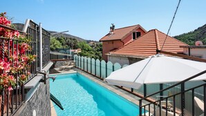 A swimming pool with a clear blue water, surrounded by a white fence, and a red-roofed building in the background. - Bed and Breakfast 'Gocce Di Cristallo' with Sea View, Wi-Fi and Air Conditioning (Varazze)