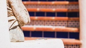 Una statua in pietra, una scalinata e un muro blu.