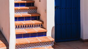 Una scala con piastrelle decorate, una porta blu e un muro bianco.