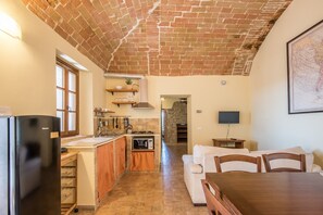 A kitchen with a brick ceiling, a refrigerator, a microwave, and a dining area with a table and chairs.