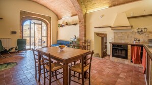 A dining area with a brick ceiling, a kitchen with an oven and a tiled backsplash, and a view through an arched doorway. - Holiday Apartment "Arianna" with Terrace & Wi-Fi (Montegabbro)