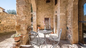 An outdoor patio with stone walls, metal chairs, a round table, and potted plants. - Holiday Apartment "Arianna" with Terrace & Wi-Fi (Montegabbro)