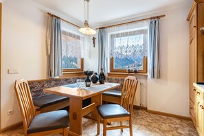 A dining area with a wooden table, chairs, and a view of mountains through the windows.