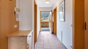 A narrow hallway with wooden cabinets, a tiled floor, and a view of a balcony with a railing. - Holiday Apartment 'Ciasa Alfred' with Mountain View, Wi-Fi & Balcony (La Villa)