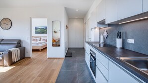 Een moderne keuken met een ingebouwde oven en een zithoek met een bank en een eettafeltje.