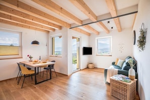 Um interior moderno com vigas de madeira, sala de jantar, sofá e televisão.