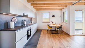 A modern kitchen with wooden beams, white cabinets, and a dining area with a table and chairs. - Holiday Apartment 'Meine Bleibe - Olive' with Mountain View, Garden & Wi-Fi (Eppan an der Weinstraße)
