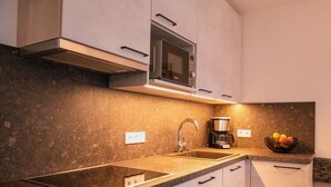 A modern kitchen with a built-in microwave, a coffee maker, and a fruit bowl on the counter. - Apartment 'Zum Sonnentor - Larix' with Mountain View, Balcony & Wi-Fi (Luttach)